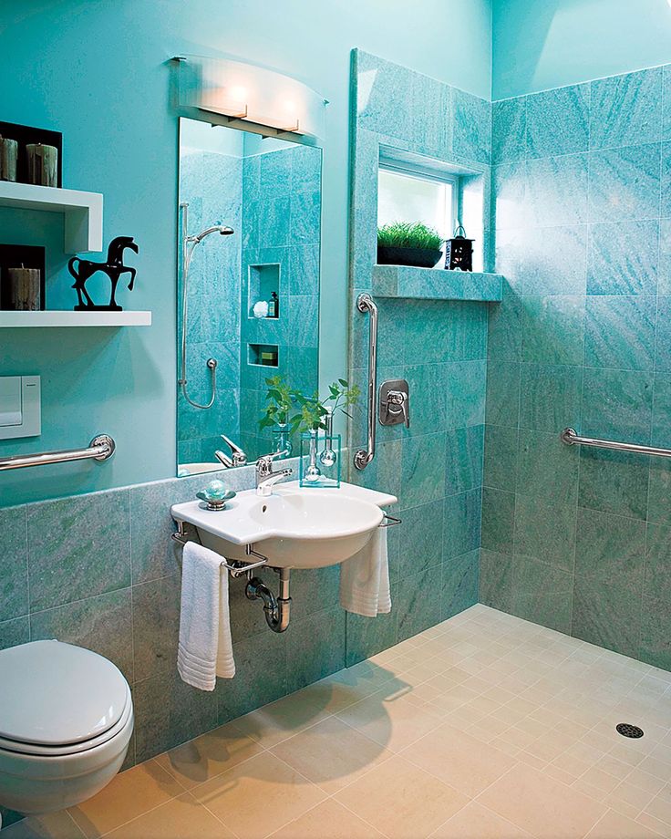 A teal bathroom with grab bars, a floating sink, and a toilet.